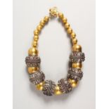 A GOOD NATIVE AND SILVER GILT NECKLACE with six large silver beads and various smaller brass beads.