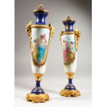 A PAIR OF SEVRES STYLE TALL PORCELAIN VASES painted with reverse panels of figures and landscapes