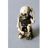 A JAPANESE MEIJI PERIOD CARVED IVORY NETSUKE OF A SKELETON, the skeleton in a seated position with