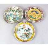 THREE CHINESE 19TH / 20TH CENTURY FAMILLE ROSE PLATES, one decorated with two dragons chasing the