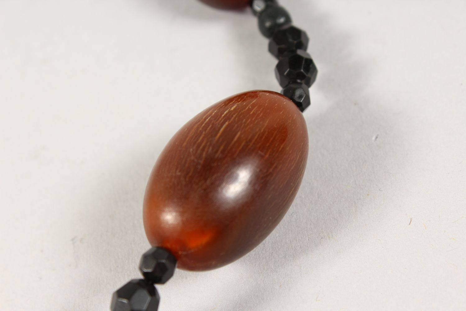 A GOOD CHINESE RHINO HORN BEAD NECKLACE, with nine oval beads of various size, interspaced with a - Image 4 of 6