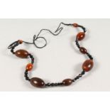 A GOOD CHINESE RHINO HORN BEAD NECKLACE, with nine oval beads of various size, interspaced with a