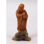 A GOOD CHINESE CARVED SOAPSTONE FIGURE OF A LUOHAN, the luohan stood holding a bottle, on a stylized