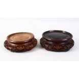 A GOOD PAIR OF 19TH CENTURY CHINESE CARVED HARDWOOD CIRCULAR STANDS, housing a vase no bigger than