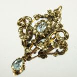 EDWARDIAN AQUAMARINE AND SEED PEARL PENDANT/BROOCH IN A YELLOW GOLD SCROLL WORK FRAME SET WITH