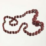 A GRADUATED STRING OF GRADUATED CHERRY AMBER BEADS, APPROX. 96 cm, LARGEST BEAD APPROX. 30 X 21 mm