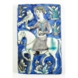 A GLAZED RELIEF DECORATED TILE WITH DEPICTING A MAN ON HORSEBACK WITH A FALCON ON A BACKGROUND