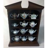 Display stand containing 12 Franklin Mint Victoria & Albert replica 18th century tea pots