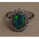 18ct white gold black opal and diamond cluster ring, central oval black opal of good colour,