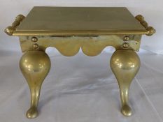 Large brass footman, the rectangular plate raised on four shaped supports with scroll handles