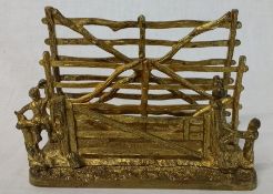 Early 20th century gilt metal letter rack in the form of rustic fences with boy and cockerel detail,