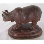 Carved rosewood model of a rhinoceros naturalistically modelled, standing on a domed plinth base L