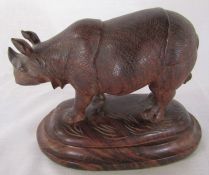 Carved rosewood model of a rhinoceros naturalistically modelled, standing on a domed plinth base L