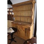 A stripped pine dresser, the upper section fitted three shelves over cupboards, on stile supports,