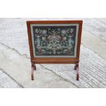 A 1920s walnut framed needlepoint fire screen, on splay supports, 24" wide