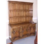 An oak dresser with plate shelves over three drawers and cupboards, on stile supports, 60" wide x