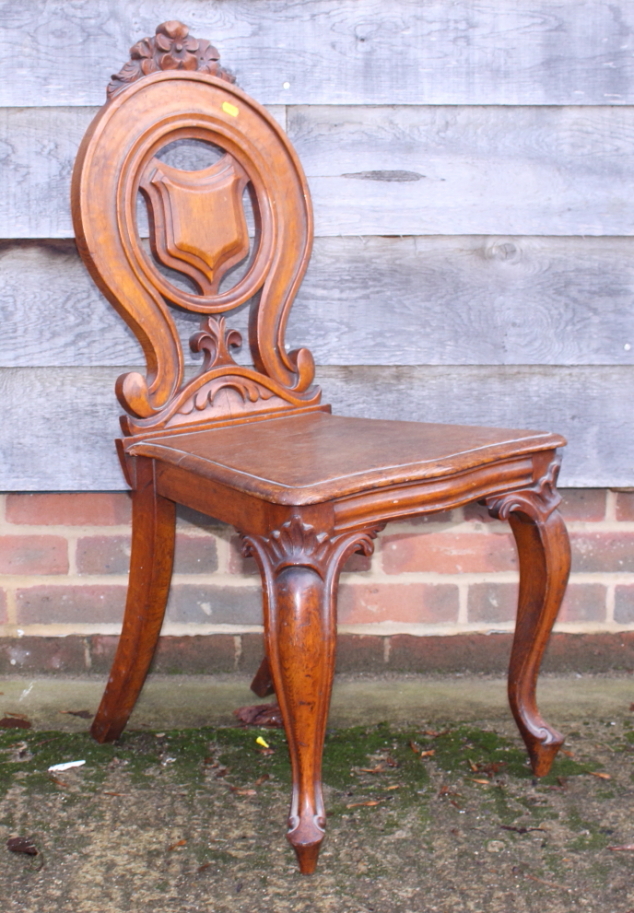 A late Victorian carved oak hall chair with shield-shape pierced back