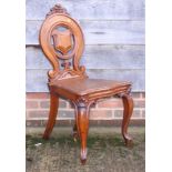 A late Victorian carved oak hall chair with shield-shape pierced back