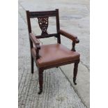 A late Victorian carved mahogany desk elbow chair with pierced splat, leather seat and arm pads, on