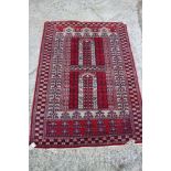 A Bokhara prayer rug with double centre and floral borders in shades of red, grey, black and