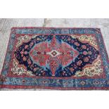 An antique Persian rug with central floral medallion on a red and blue ground with floral borders in