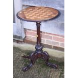 A Victorian walnut games table with chess board top, on fluted column and tripod splay support,