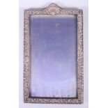 A silver mounted picture frame with embossed decoration and bevelled plate, 13" x 8"