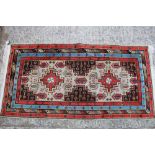 A Hamadan type rug with two cruciform guls on a fawn ground and multi-bordered in shades of red,