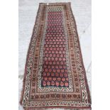 A Persian tribal runner with all over boteh design on a blue ground in shades of red, brown, green