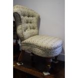 A Victorian low seat nursing chair with scroll back, button upholstered in a floral fabric, on