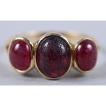 A yellow metal three stone ring set ruby cabochons, ring size R (wear to stones)
