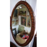 A 1930s carved oak oval framed bevelled edge wall mirror, plate 34" x 22", and a smaller, similar,