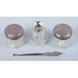 Two silver topped dressing table jars, a glass scent bottle and stopper with silver collar and a