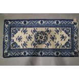 A Tibetan? blue and white rug of traditional design, 50" x 25 1/2" approx