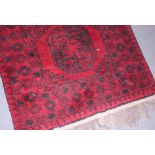 An Afghan Bokhara rug with six central medallions and multi-borders on a red ground, 113" x 35"