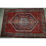 A Tabriz type rug with central lozenge on a red ground and multi-bordered in shades of red, blue,