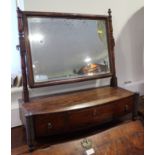 An early 19th century figured mahogany swing frame toilet mirror, on bowfront plateau base, fitted