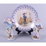 A pair of Continental porcelain figures, flower sellers, and a tin glazed plate, "Auvergne"