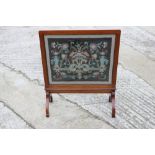 A 1920s walnut framed needlepoint fire screen, on splay supports, 24" wide, and a mahogany reeded