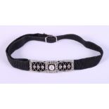 An Art Deco white metal bracelet mount, set diamonds and single pearl, on black fabric strap with