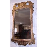 A gilt framed wall mirror of early Georgian design, with bevelled arch top plate and shell crest,