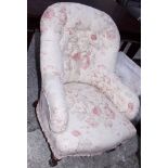 A late Victorian tub shape armchair, button upholstered in a floral fabric, on turned supports