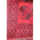 An Afghan Bokhara rug with five central medallions on a red ground and geometric multi-border