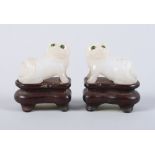 A pair of Chinese pale celadon jade Dogs of Fo with green inlaid eyes, on carved wooden bases, 1 3/