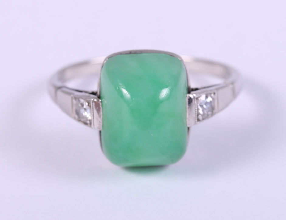 A white metal mounted jade cabochon ring, set diamonds to shoulders, ring size M/N