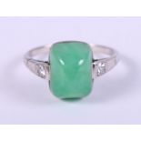 A white metal mounted jade cabochon ring, set diamonds to shoulders, ring size M/N