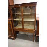 An early 20th century walnut display cabinet enclosed two doors and one drawer, on square taper