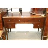 An Edwardian mahogany kneehole desk, fitted two small and two long drawers, on square taper