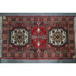 A rug decorated with two elephant feet on a red ground with multi-border stripes, 53" x 33" approx