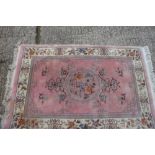 A Chinese contour pile rug of traditional design on a pink ground, 42" x 74" approx